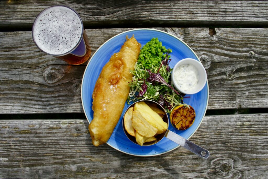 Enjoy the Classic Fish and Chips with a Twist of Curry and Peas